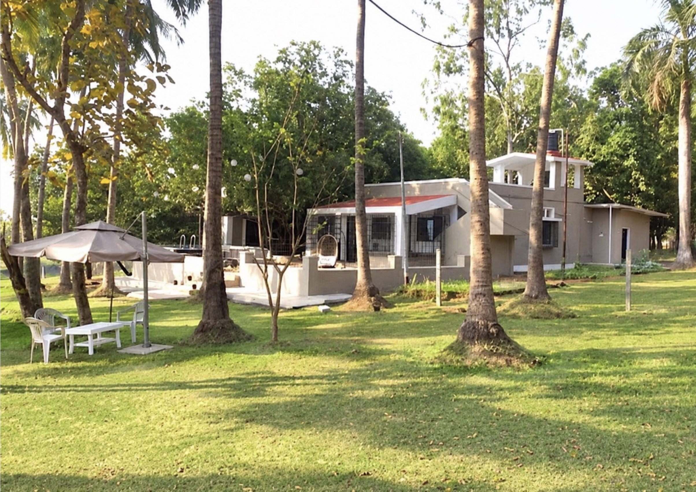 The farmhouse and grounds at Riverwood Retreat Karjat, surrounded by greenery